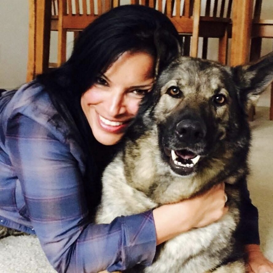 Woman hugging a large German Shepherd dog indoors.